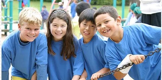 Four children in blue shirts smiling at the camera