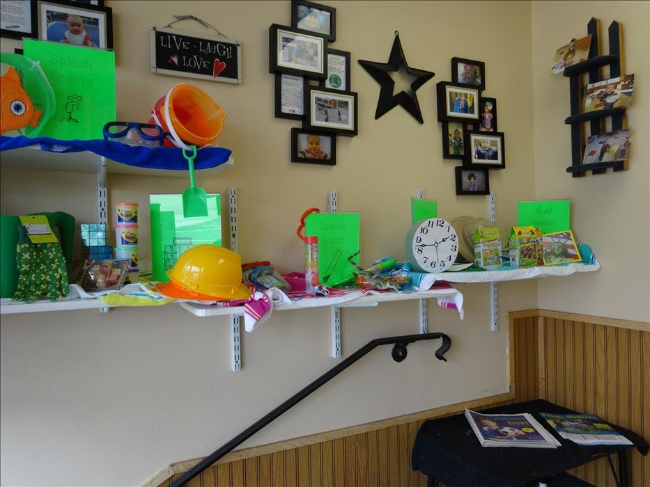 Shelves with various toys, games, and framed photos on a wall