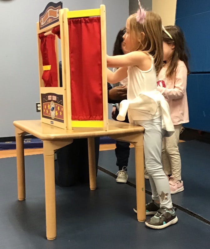 Child playing with a puppet theater on a table