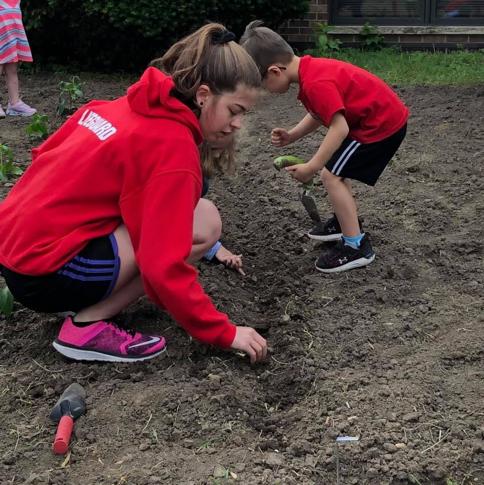 Teen and child planting in a garden