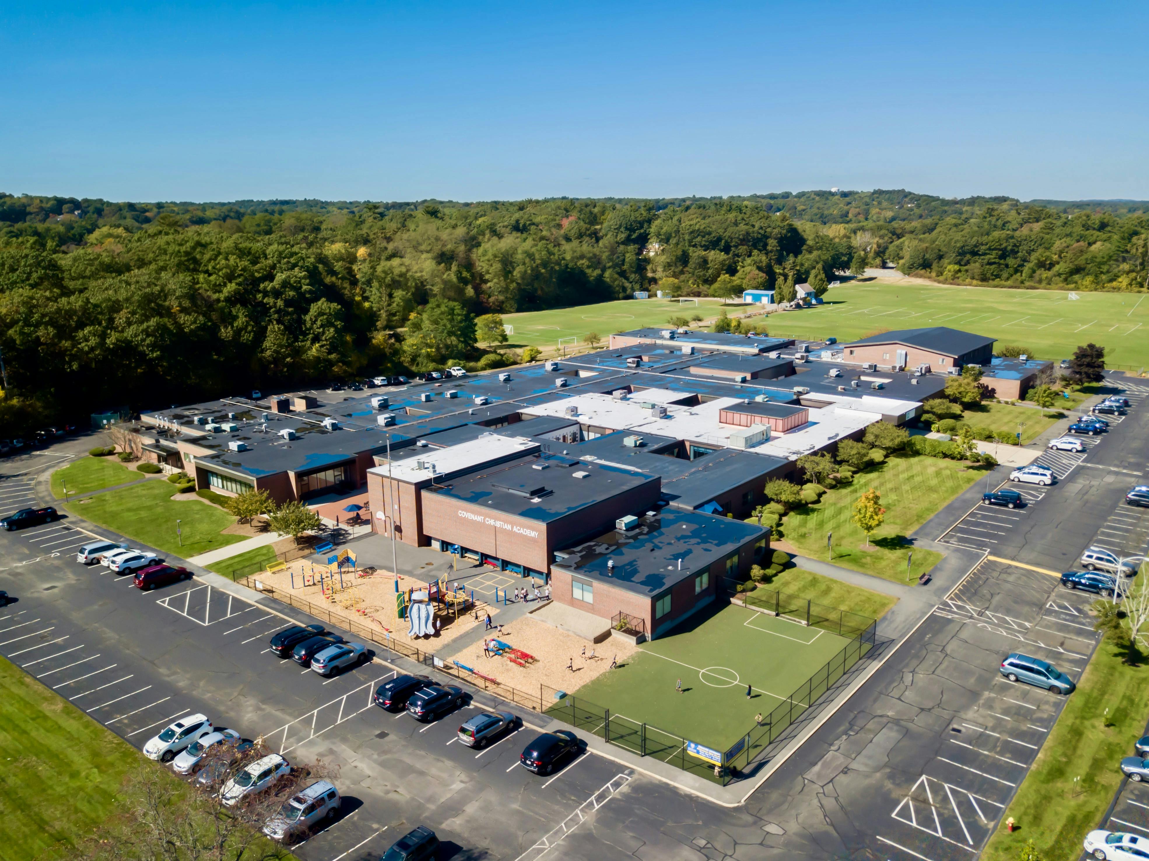 Aerial view of a school building with a playground and parking lots