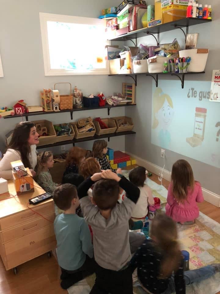 Adult and children watching a projected image on a wall in a classroom