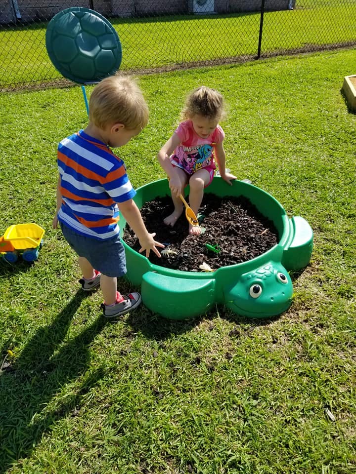 Two children playing in a turtle-shaped sandbox