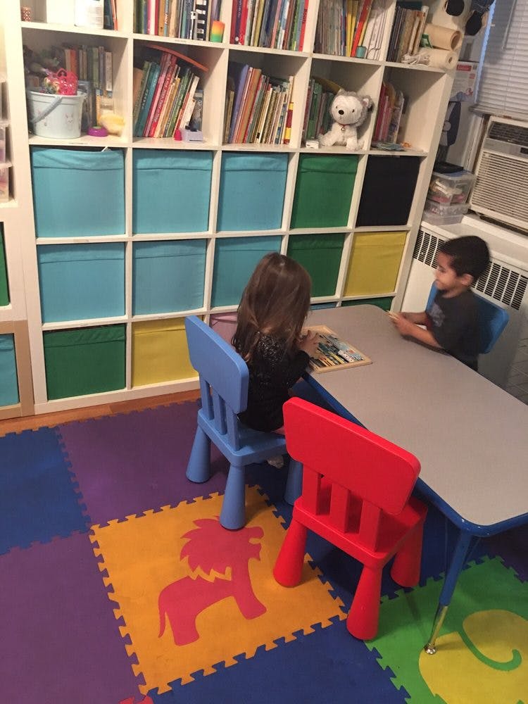 Two children sitting at a small table in a playroom