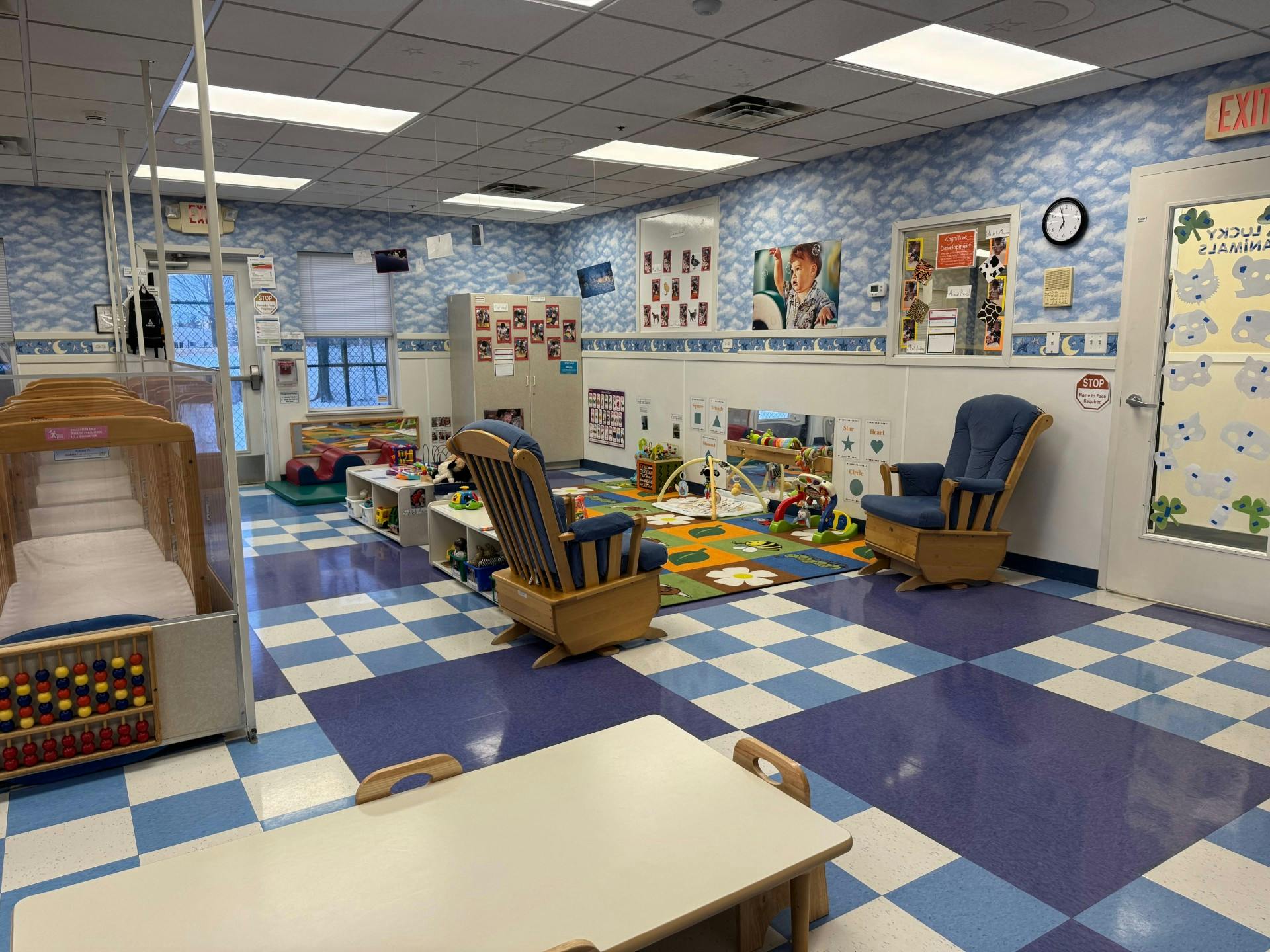 Empty colorful playroom with two rocking chairs, cribs, small tables, and toys