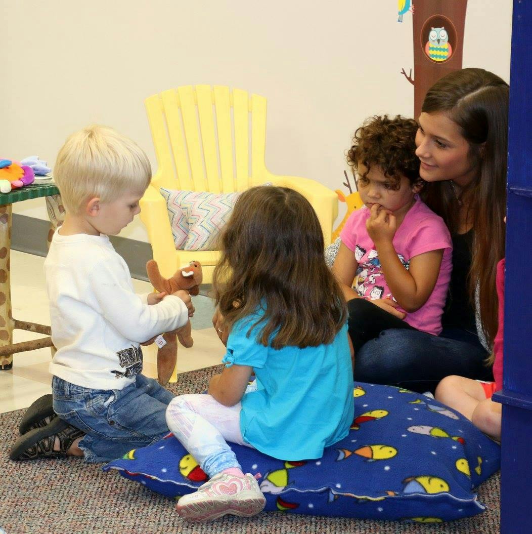 Adult and three children sitting on floor, one child holding a toy