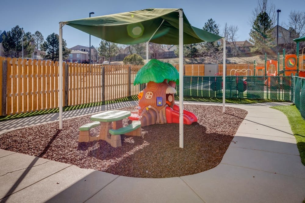 Playground area with a small slide, picnic table, and shade canopy