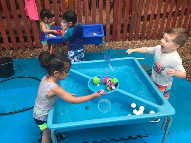 Children playing with water tables outdoors