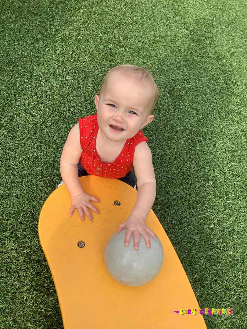 Child in red shirt playing with a ball on a yellow surface