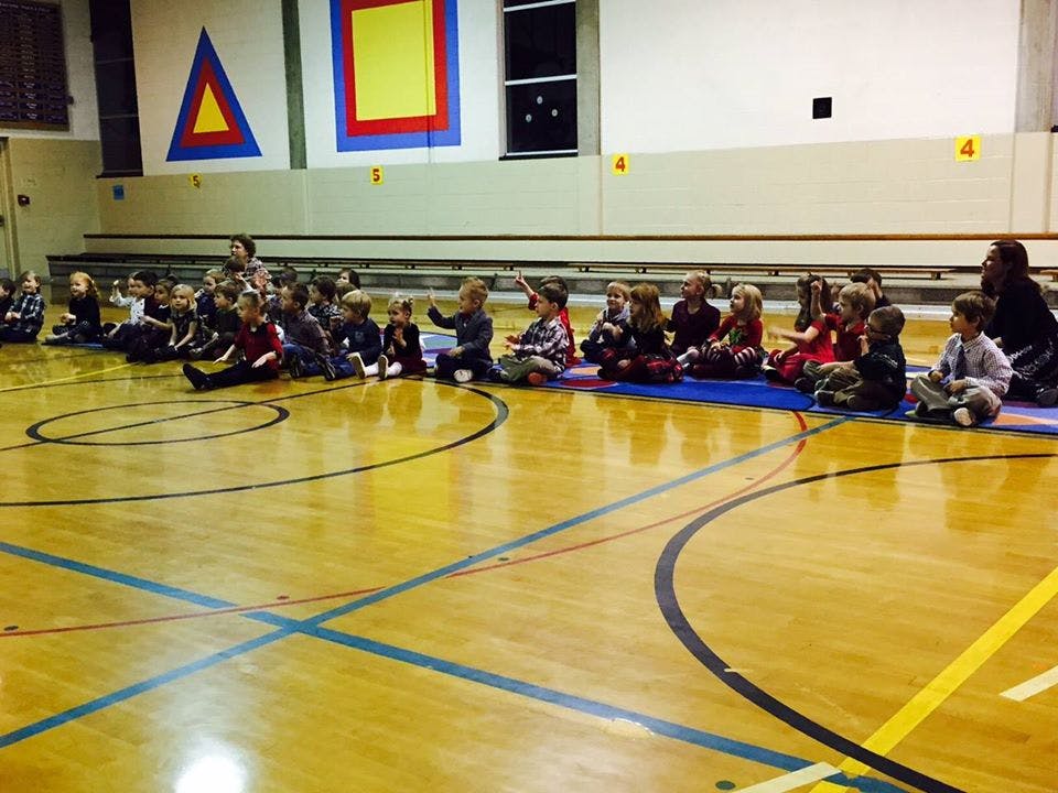 Group of children sitting on mats on a gymnasium floor
