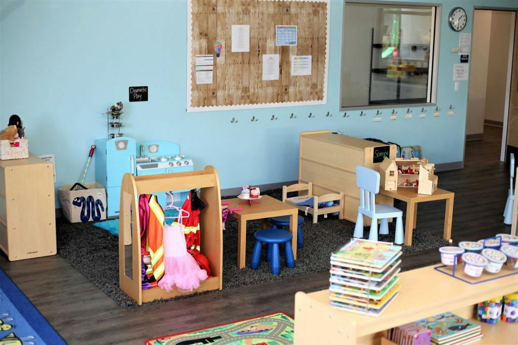 Playroom with small tables, chairs, and dress-up clothes