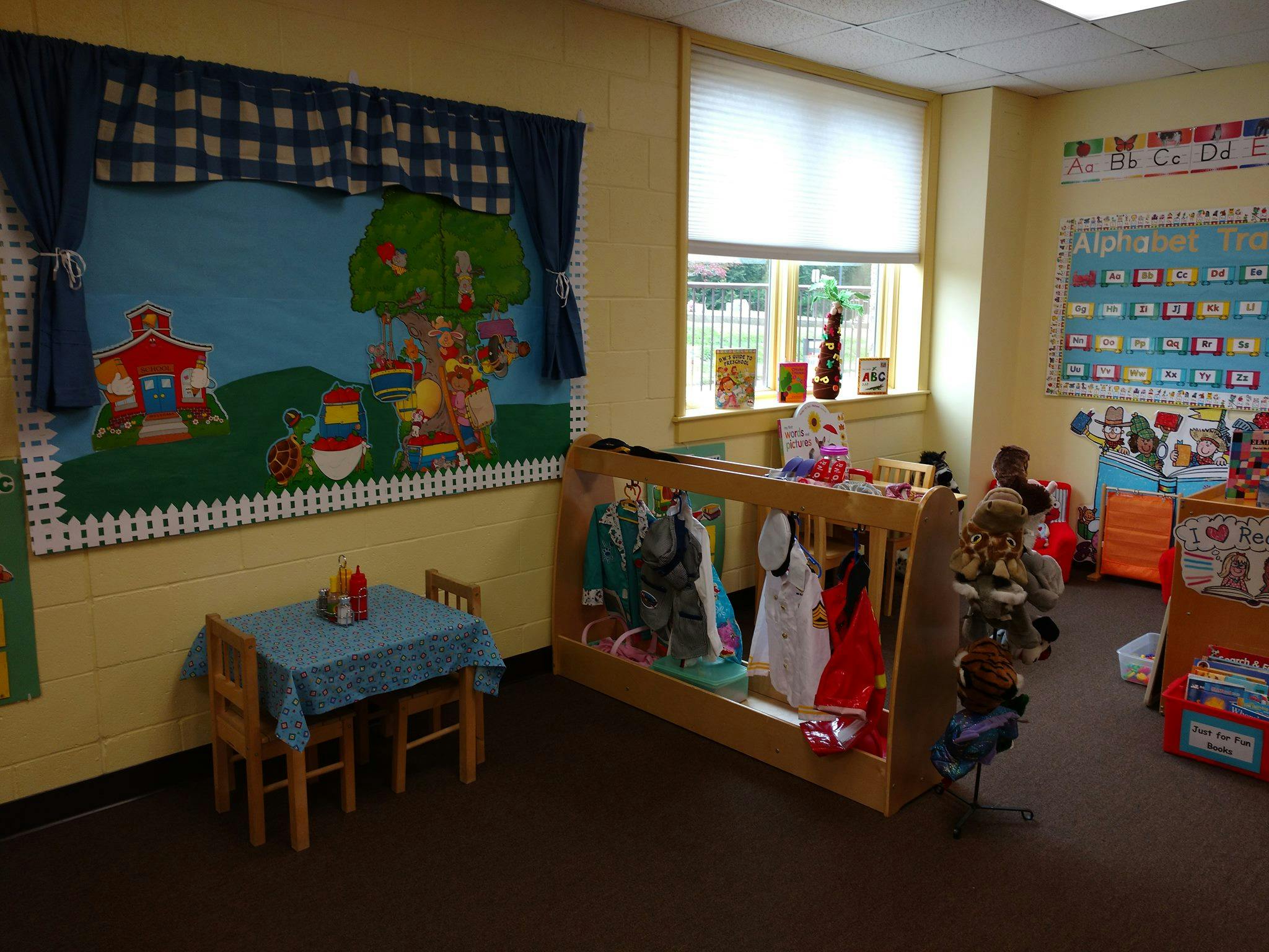 Classroom with a small table and chairs, dress-up clothes rack, and window
