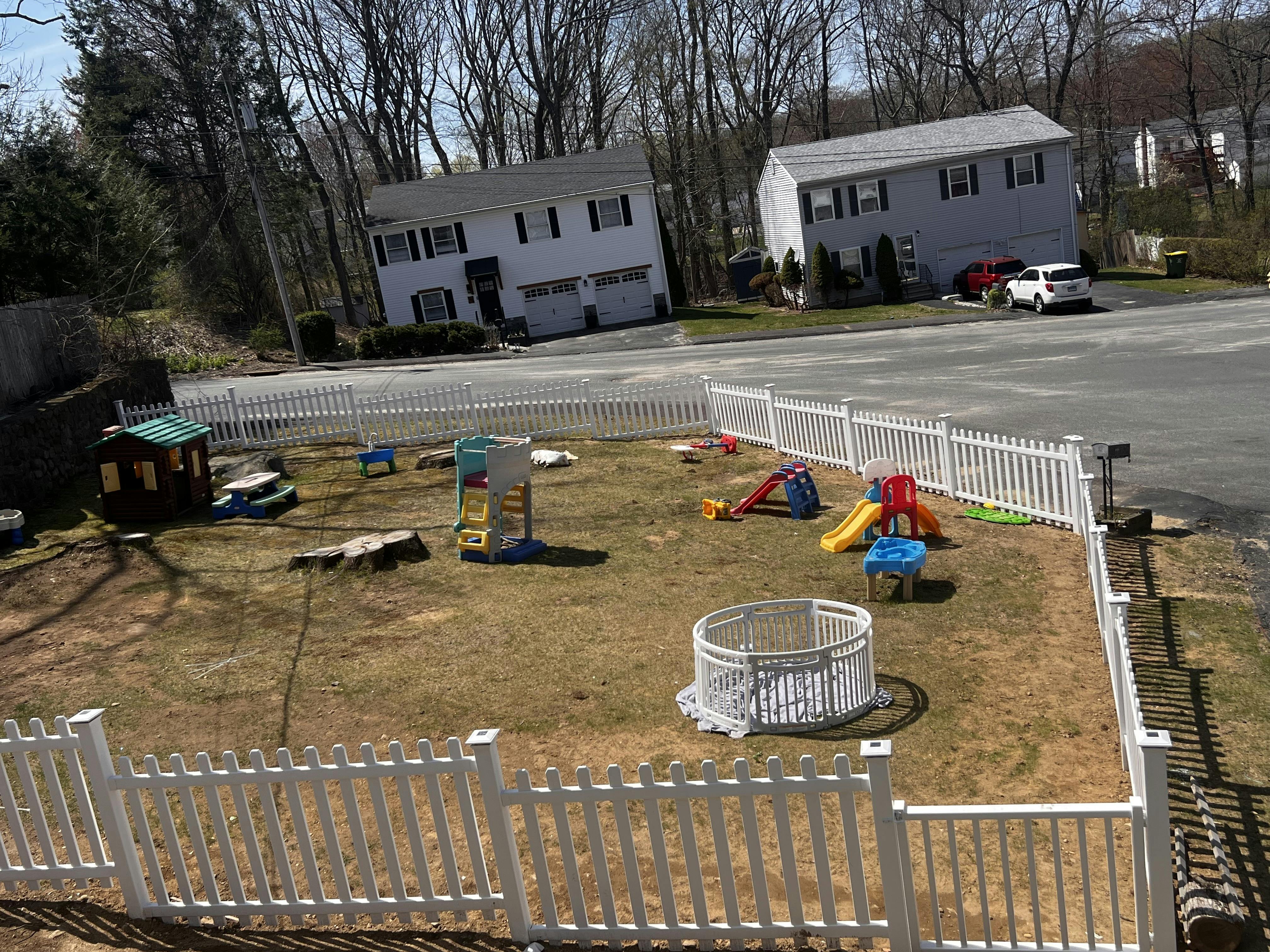 Backyard with a white picket fence and various playground equipment