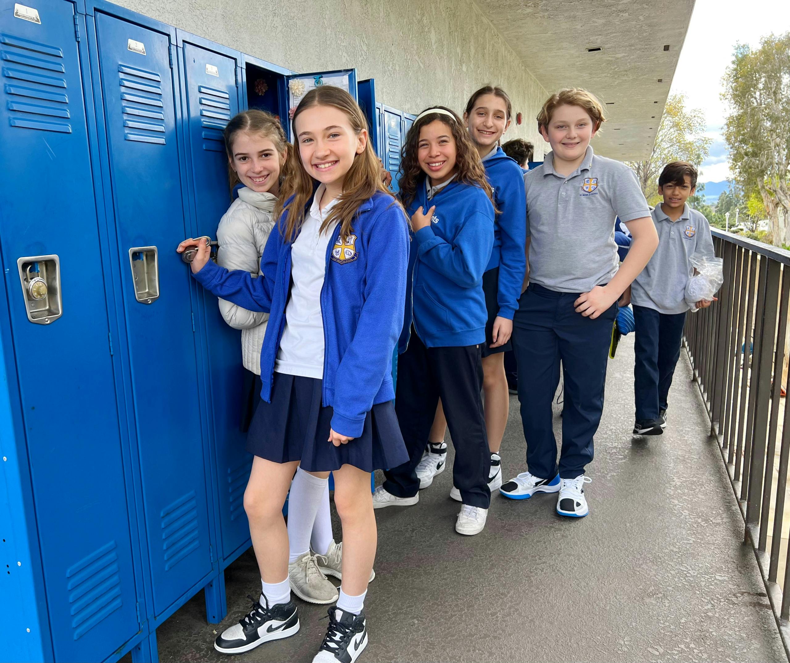 Group of children standing in a row next to blue lockers