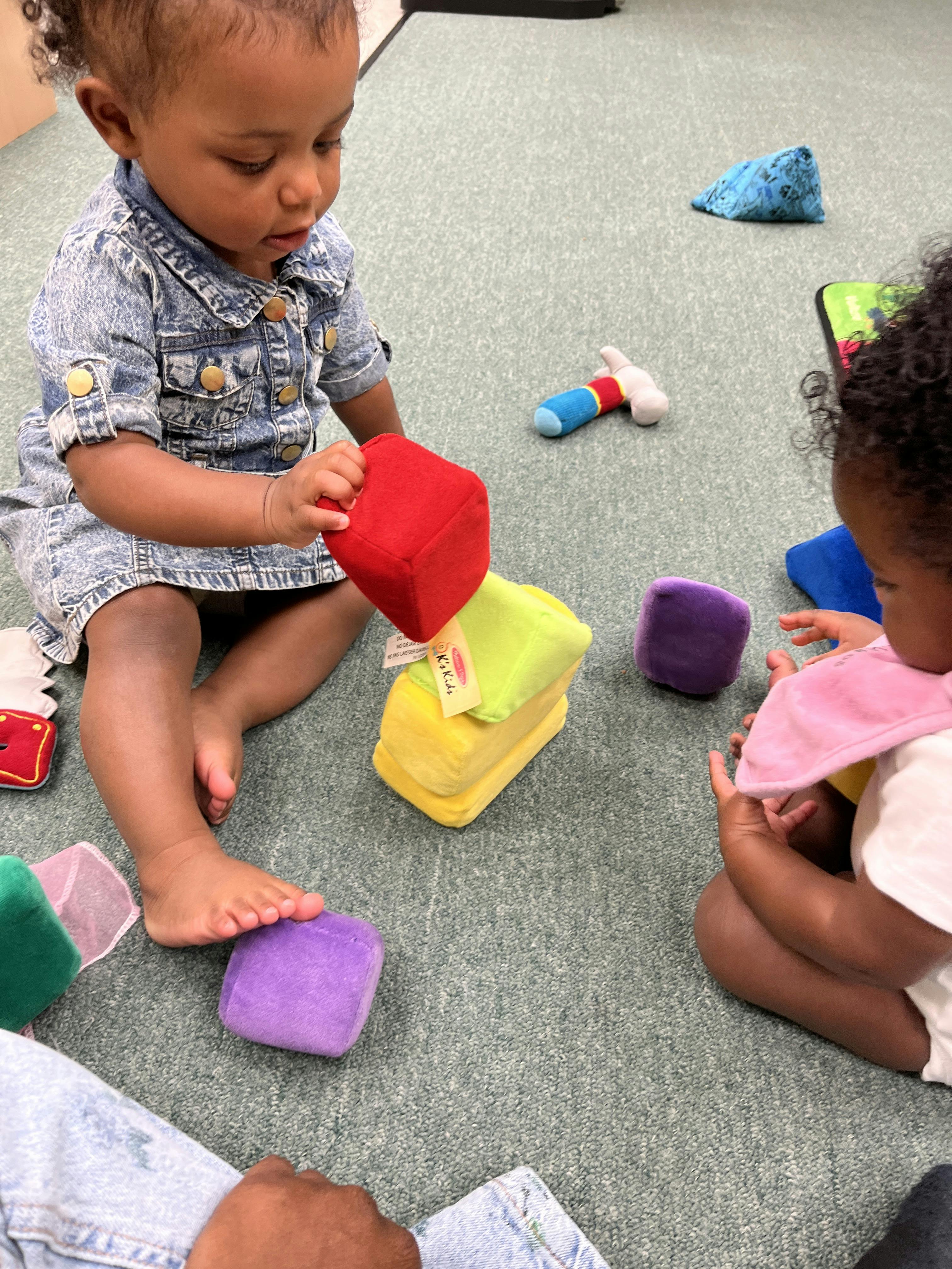 Child stacking colorful soft blocks on a carpeted floor