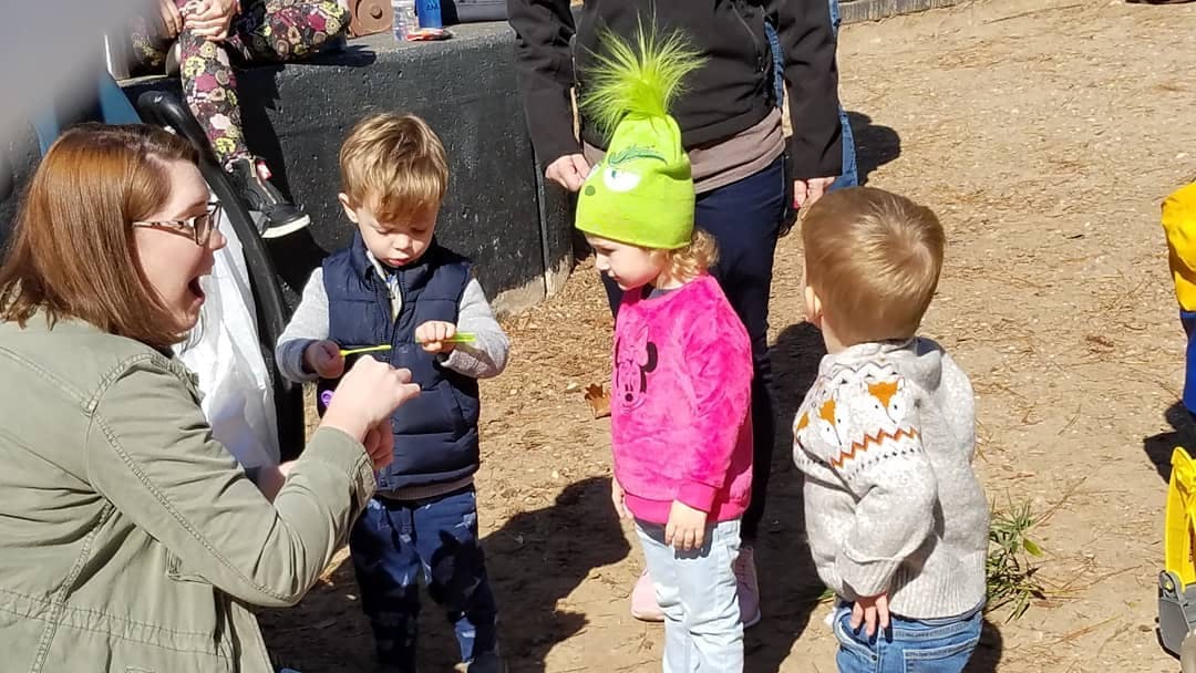 Adult person interacting with three children outdoors