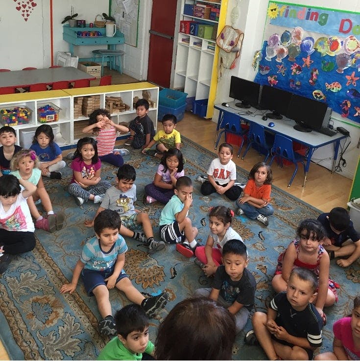 Group of children sitting on a rug in a classroom