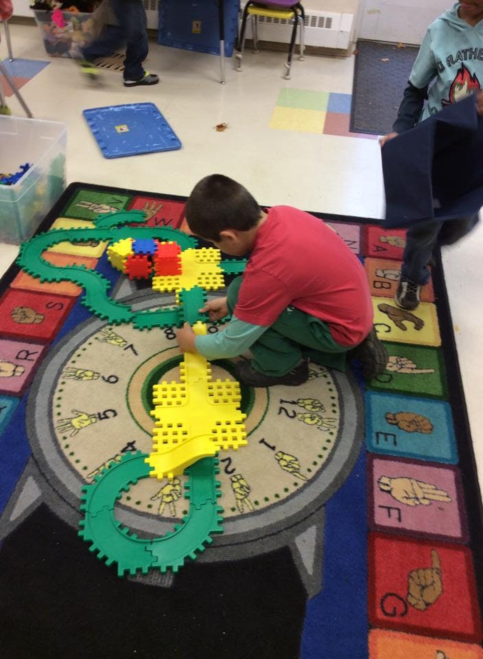 Child playing with interlocking gear toys on a rug