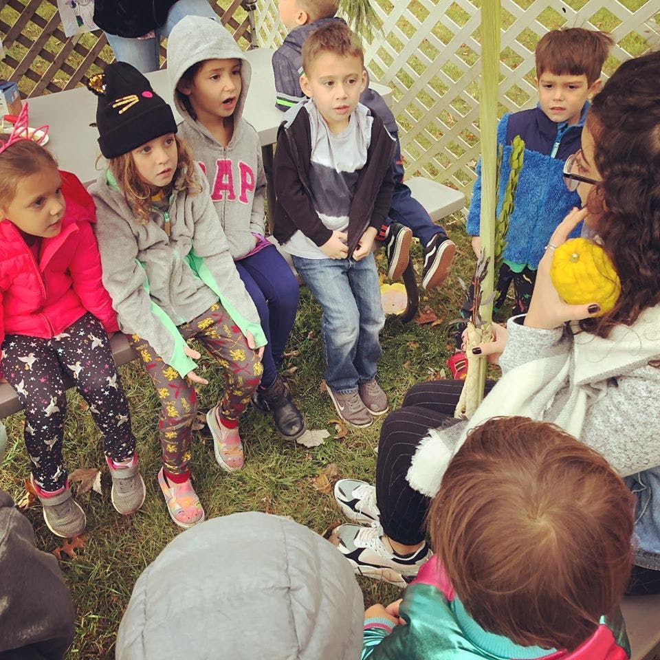 Adult speaking to a group of children sitting on a bench