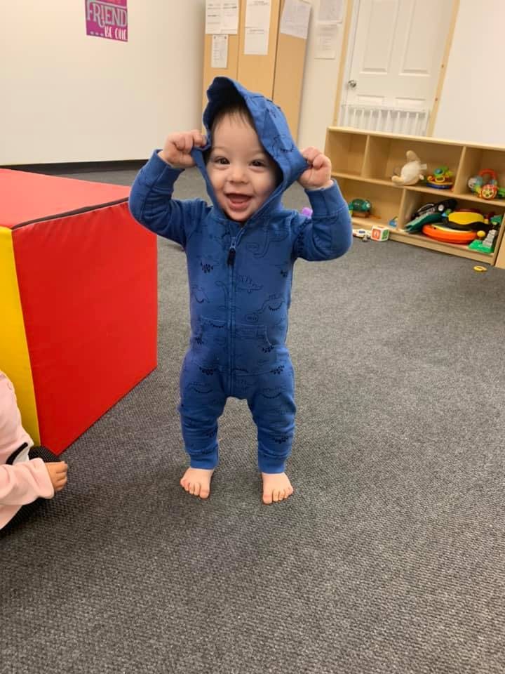Child in blue hooded jumpsuit standing on carpet