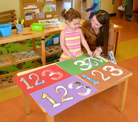 Adult and child pointing at large numbers on a table