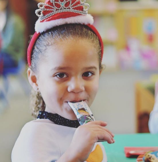 Child wearing a crown headband and eating from a pouch