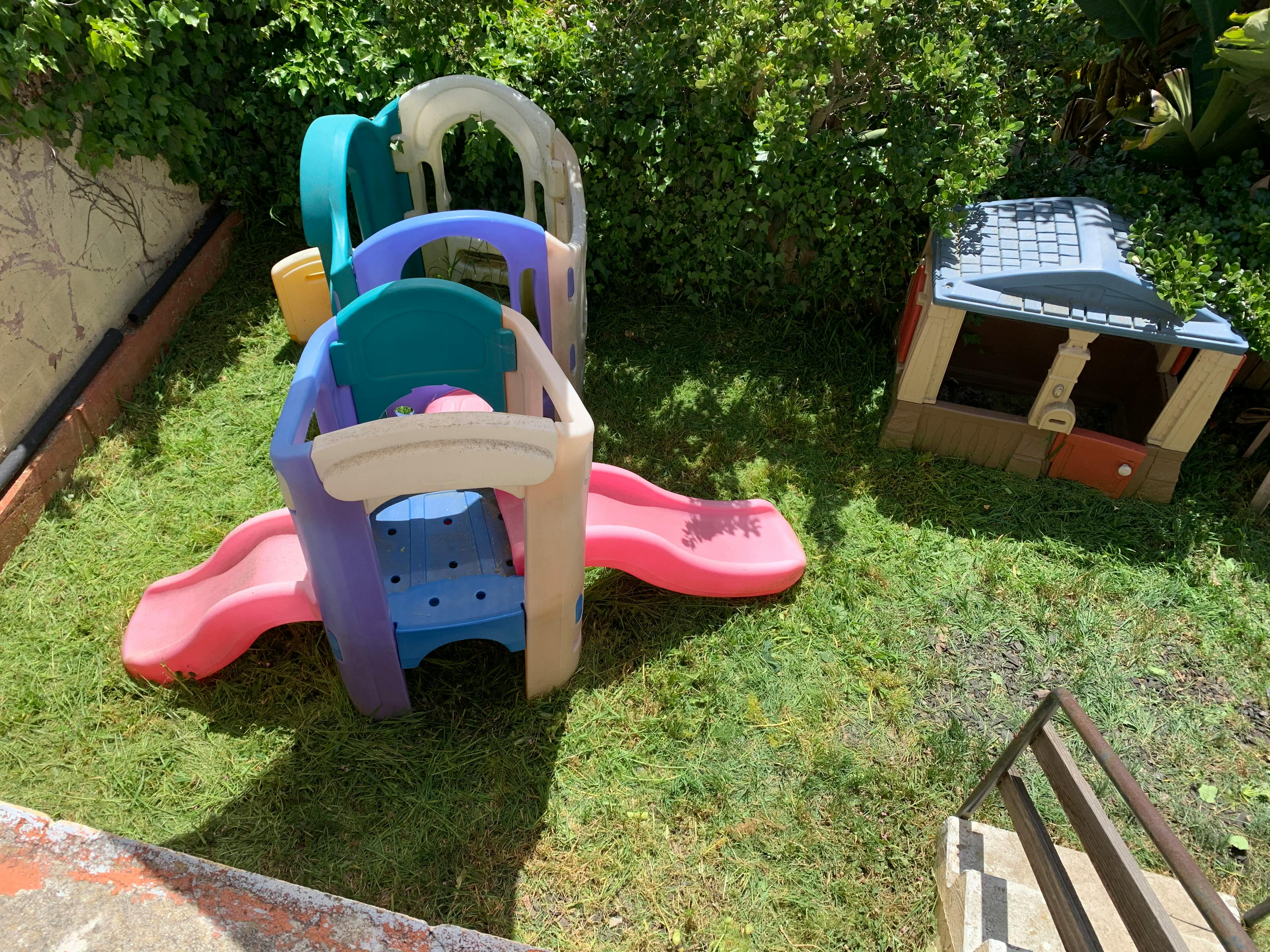 Children's play structure with slides and a small playhouse on grass