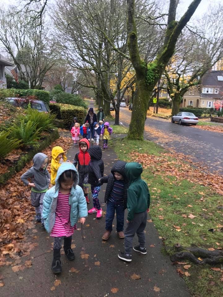 Group of children and adults walking on a sidewalk