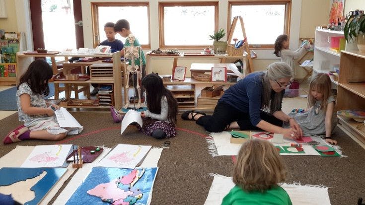 Adult and children working on floor in classroom