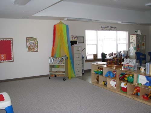 Classroom with a rainbow canopy, book cart, and shelves with toys