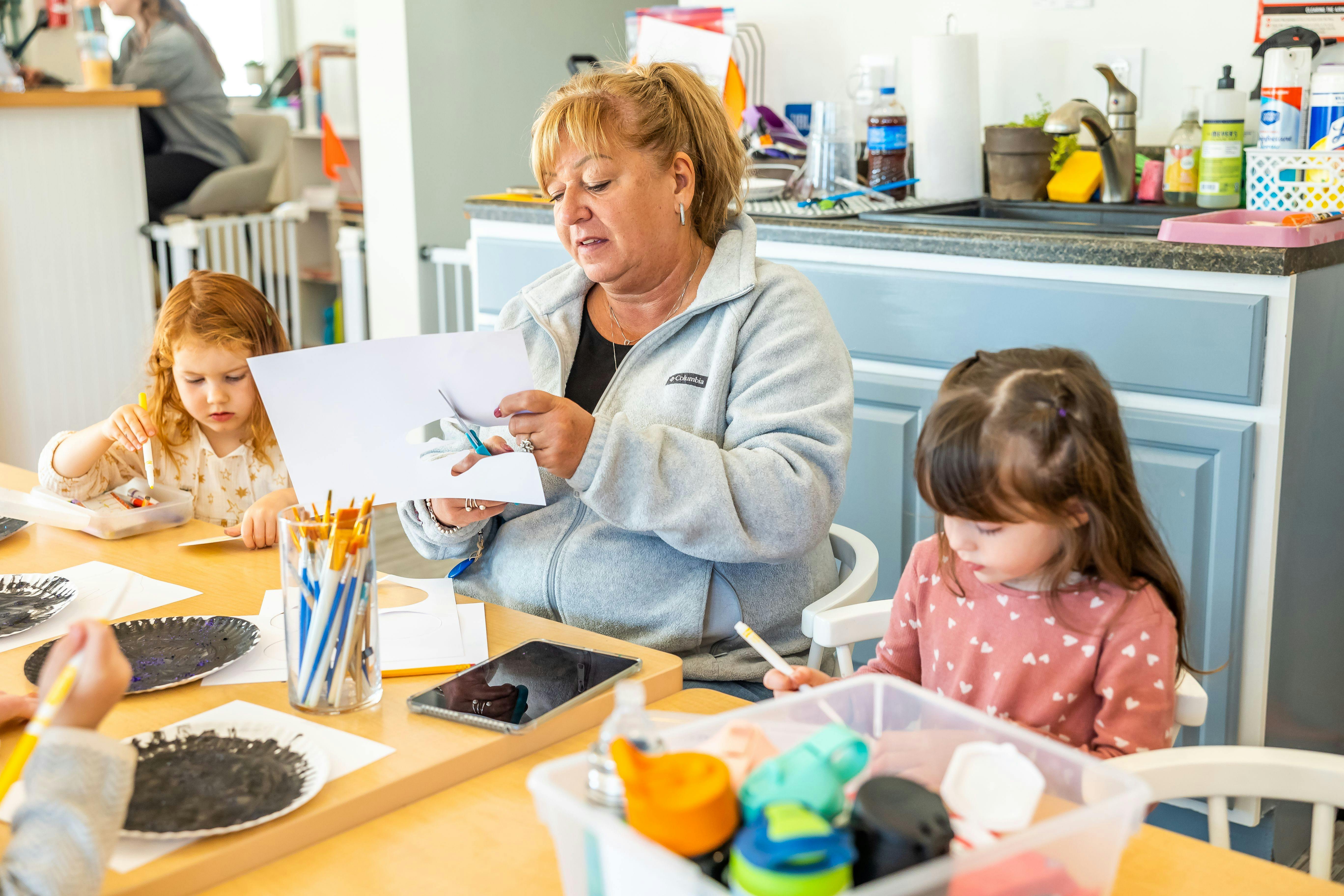 Adult and two children at a table with art supplies