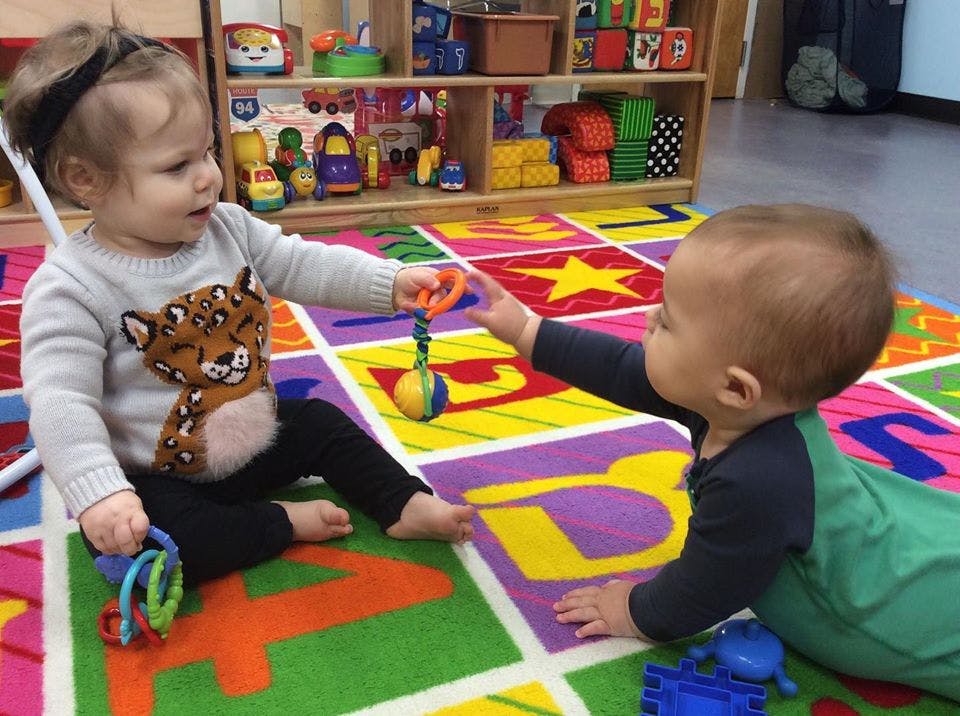 Two children playing with toys on a colorful alphabet rug