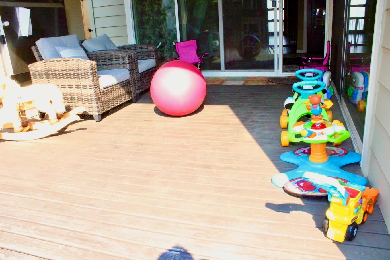 Outdoor deck with a pink exercise ball, rocking horse, and child's toys