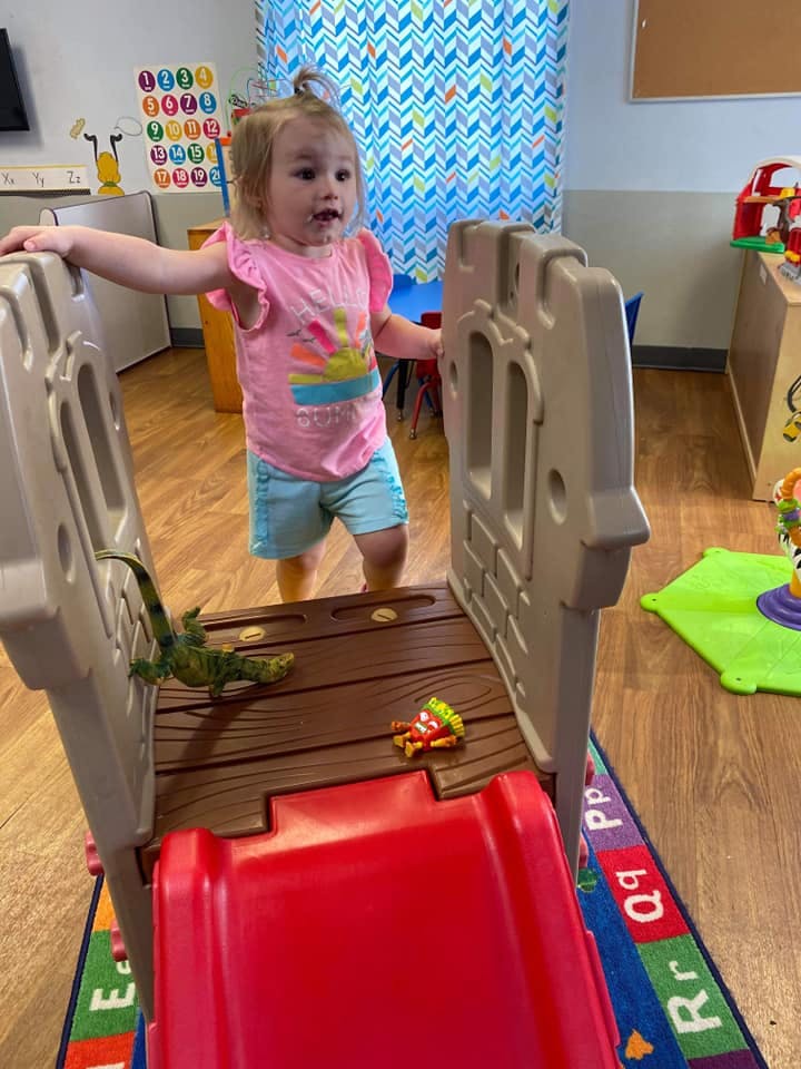 Child standing on a play structure with a red slide