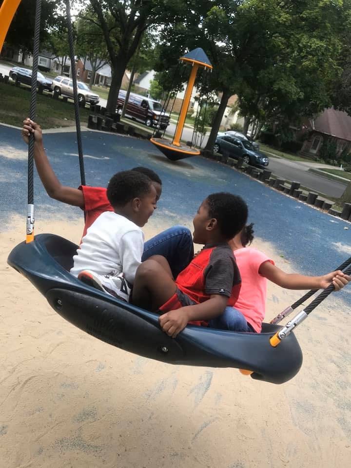 Three children on a swing at a playground