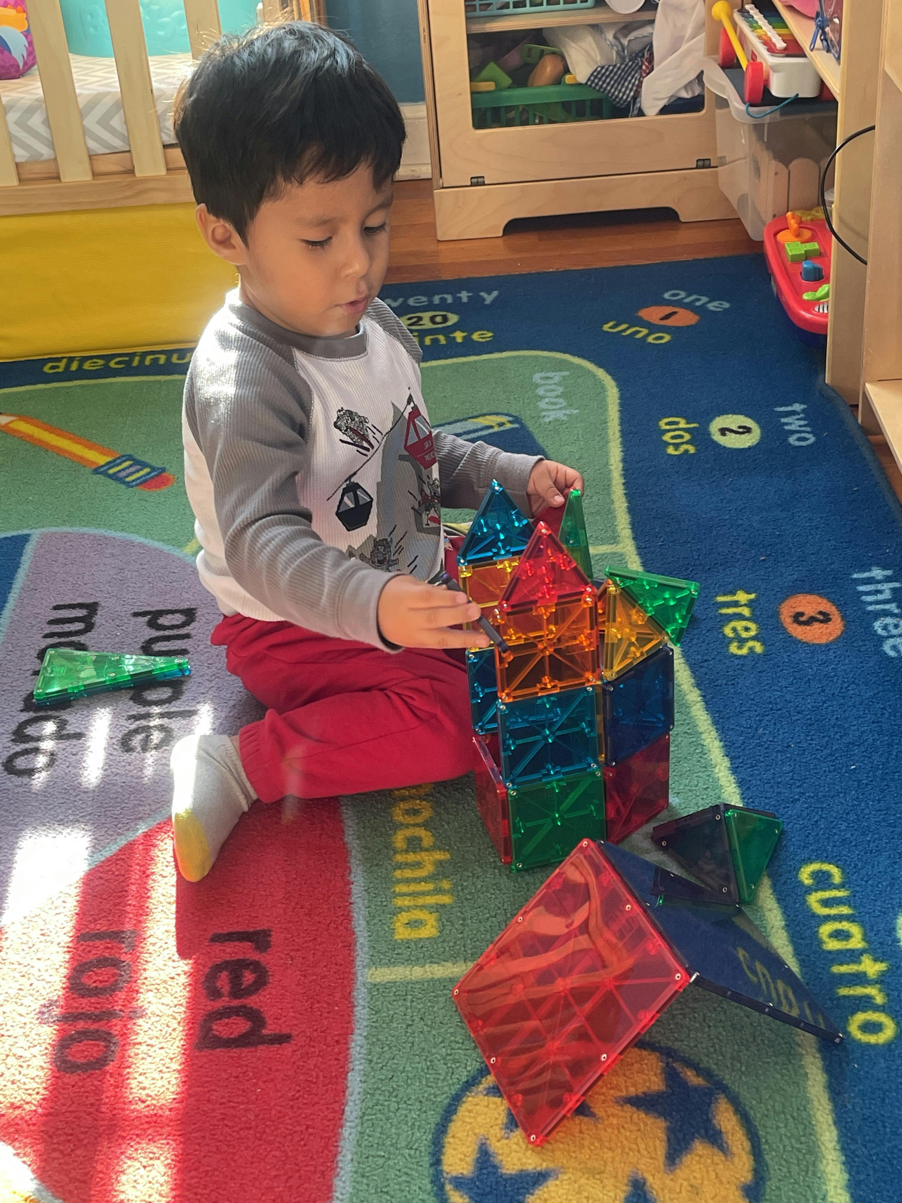 Child playing with colorful magnetic building blocks on a rug