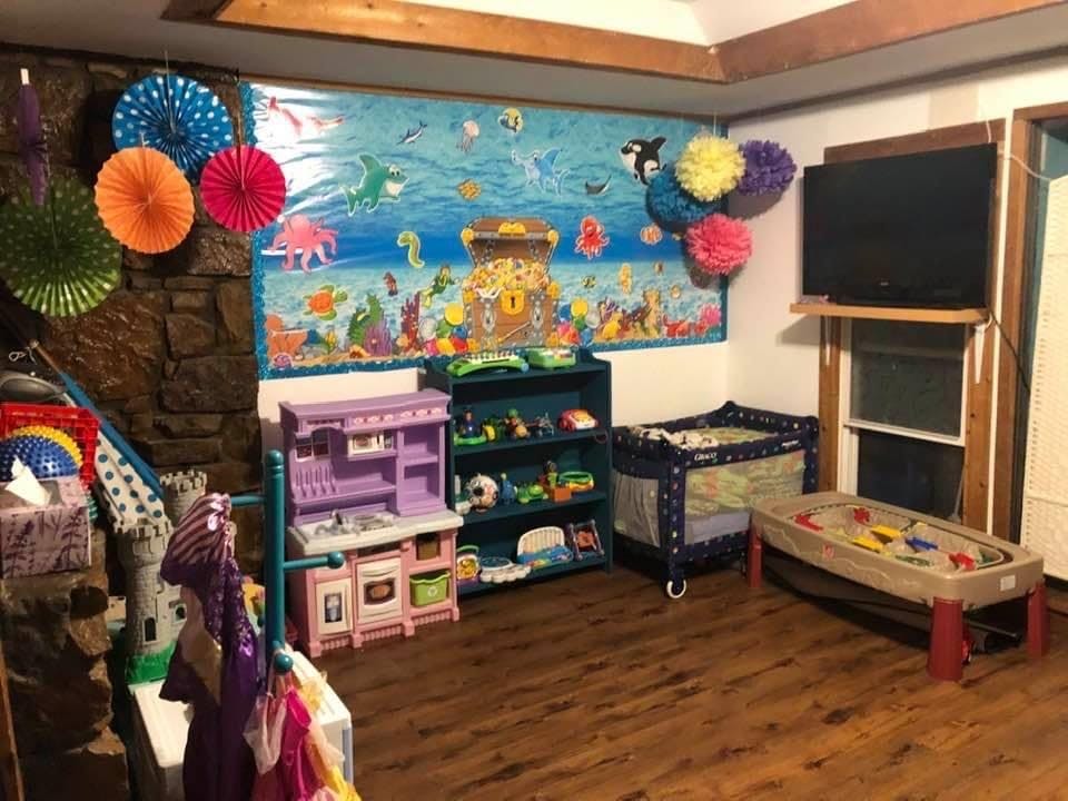 Playroom with toys, crib, and an ocean-themed mural