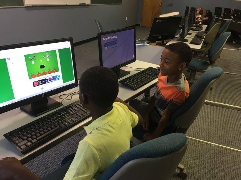 Two children sitting at computers in a classroom