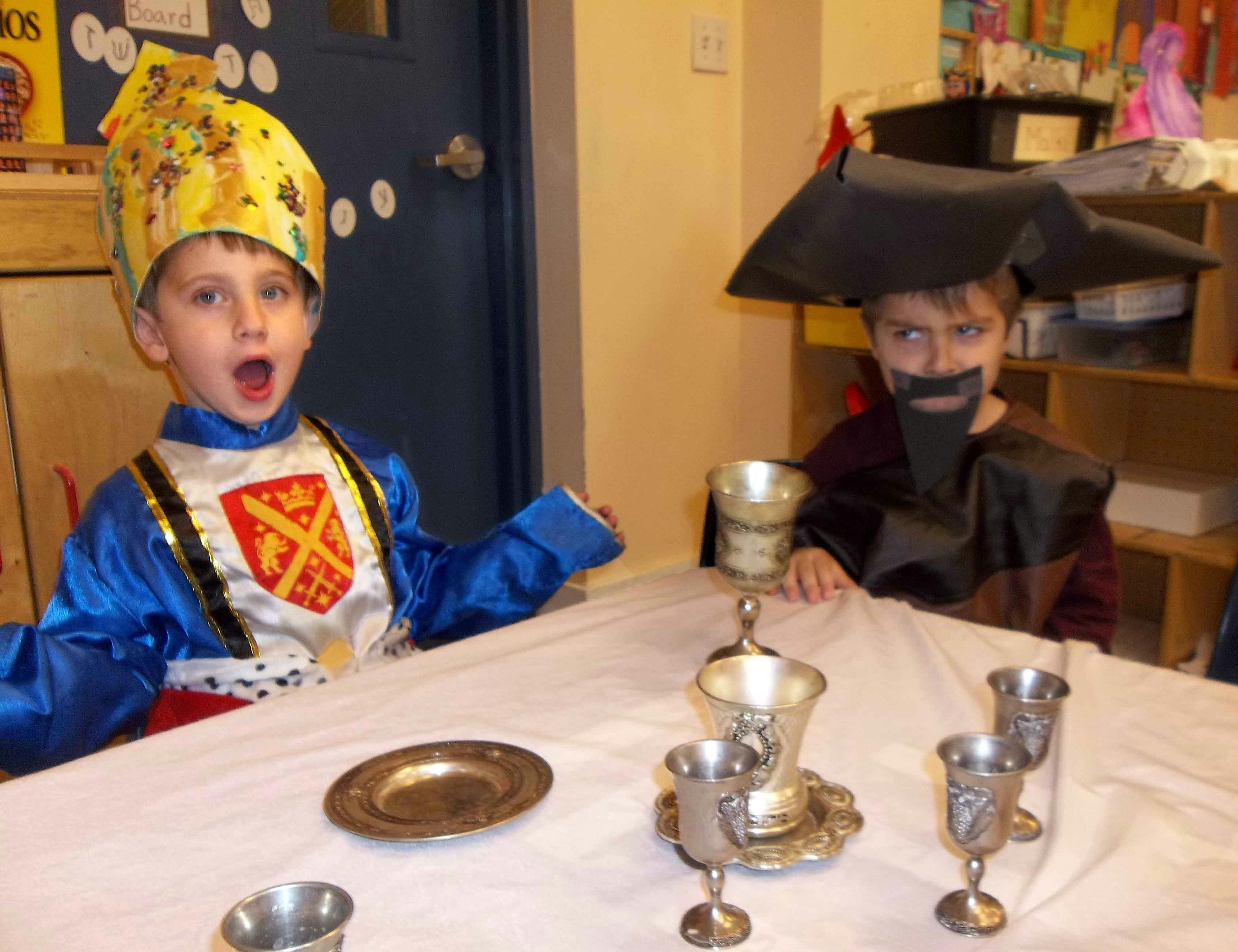 Two children in costumes sitting at a table with goblets