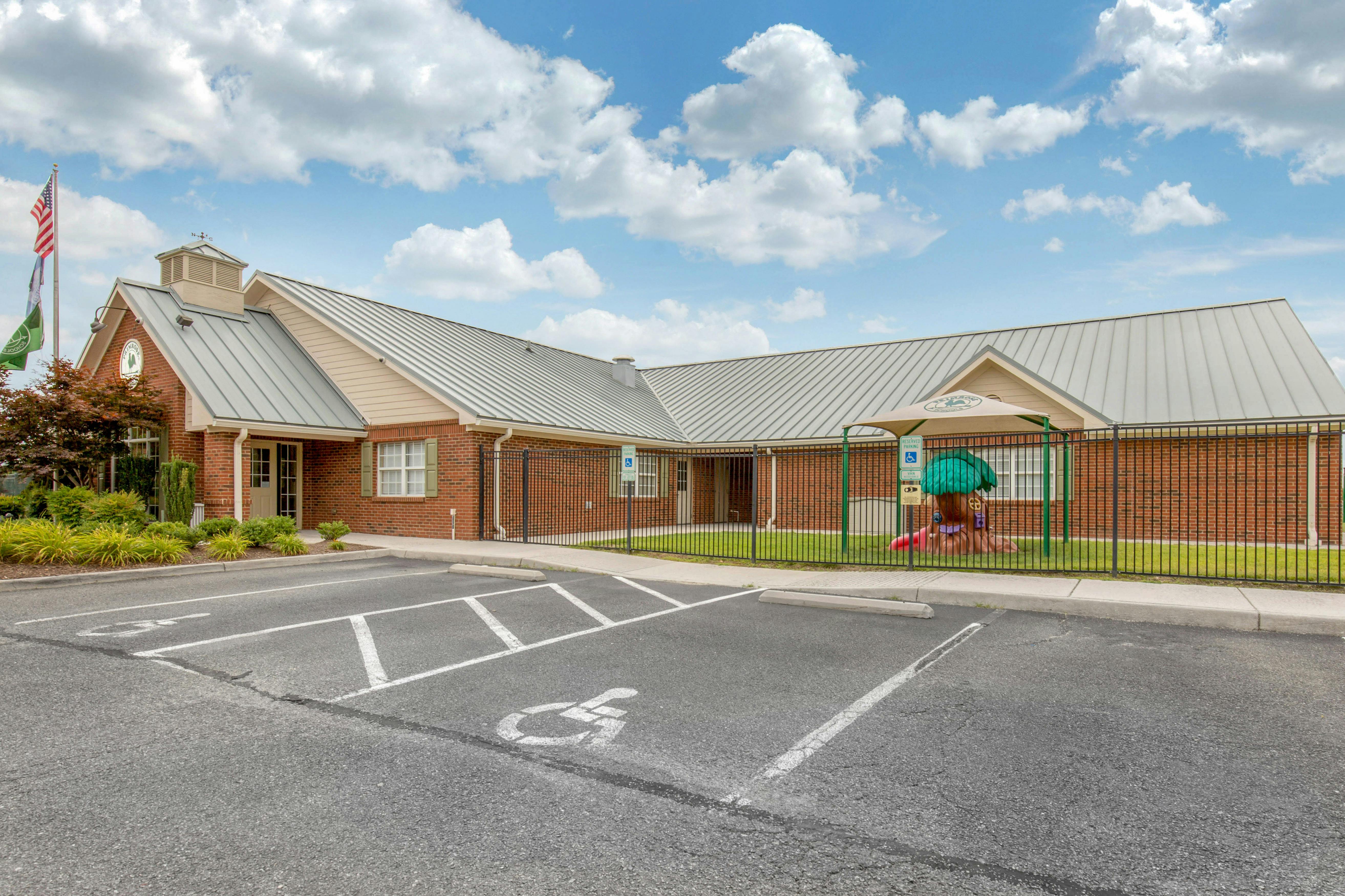 Brick building with a metal roof, parking lot, and fenced playground