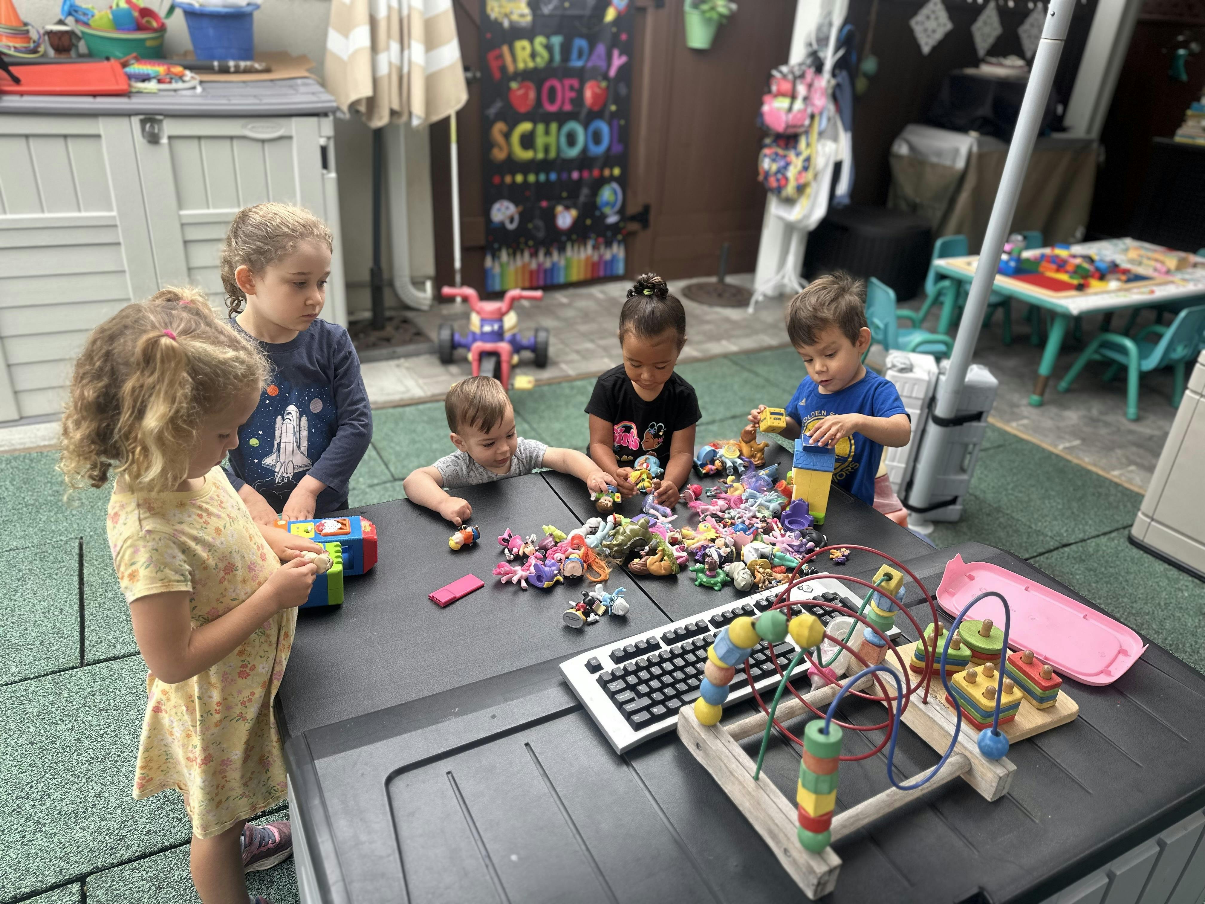 Group of children playing with toys at a table outdoors