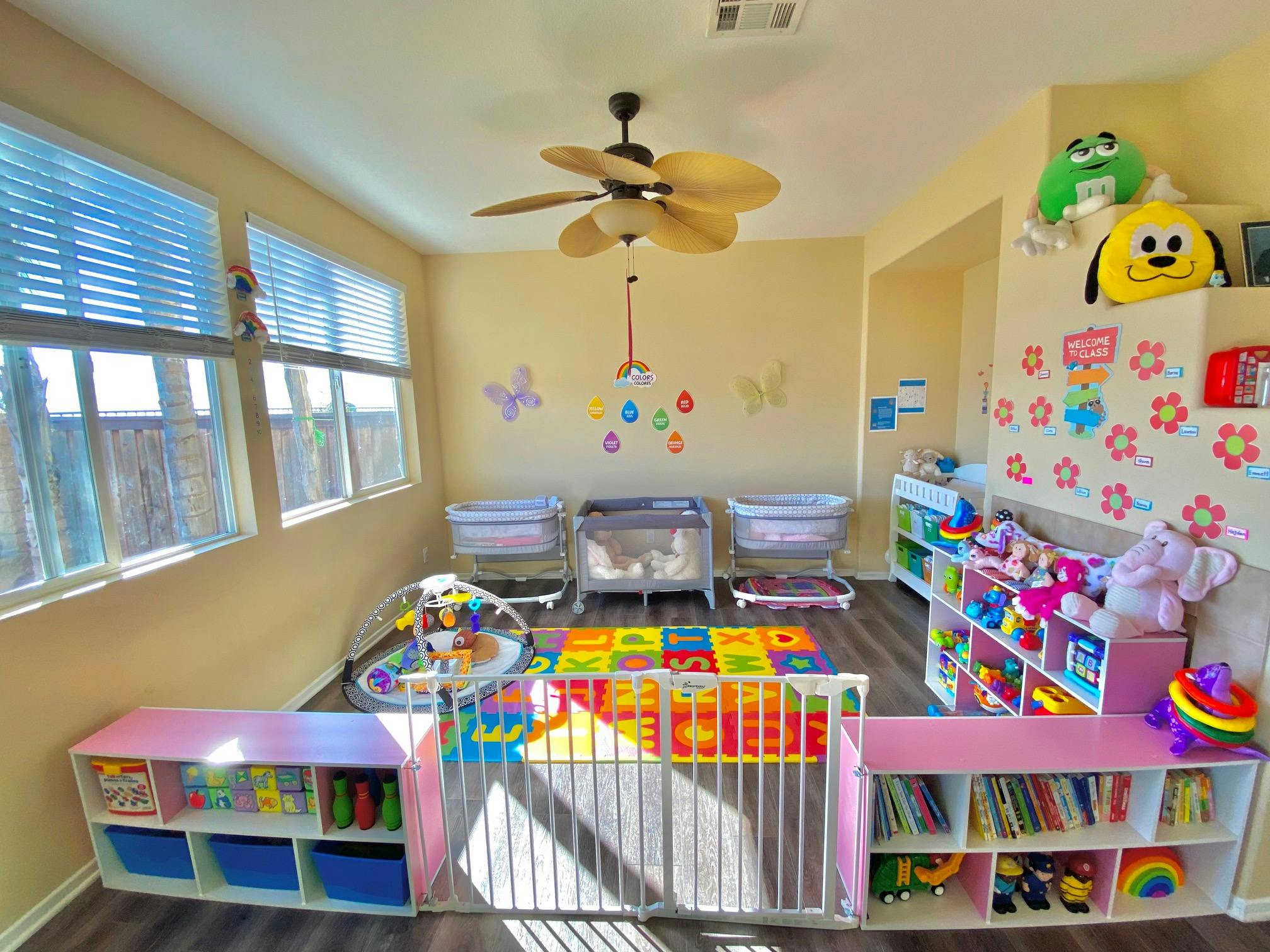 Daycare room with cribs, play mats, and shelves of toys