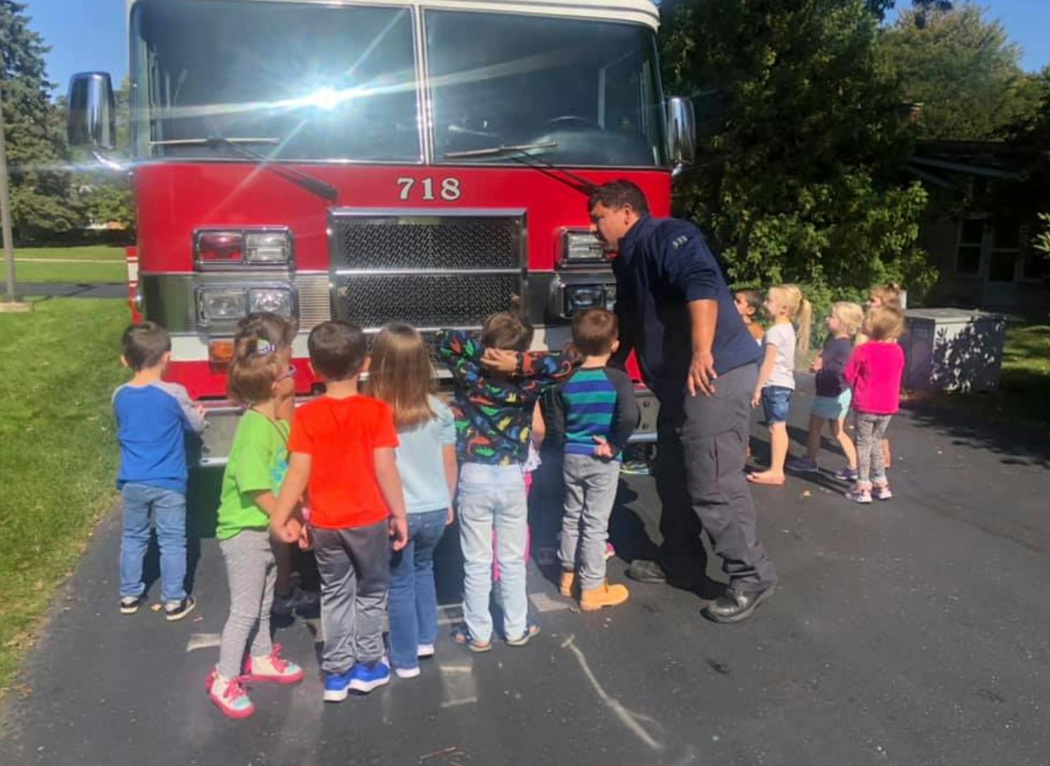 Adult speaking to children in front of a fire truck