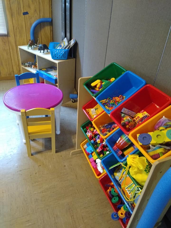 Children's play area with a purple table, chairs, and toy storage bins