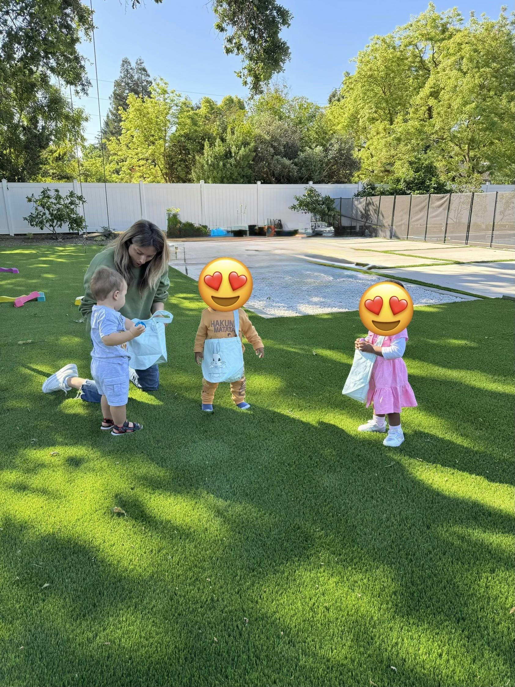 Adult and three children holding bags on a grassy lawn