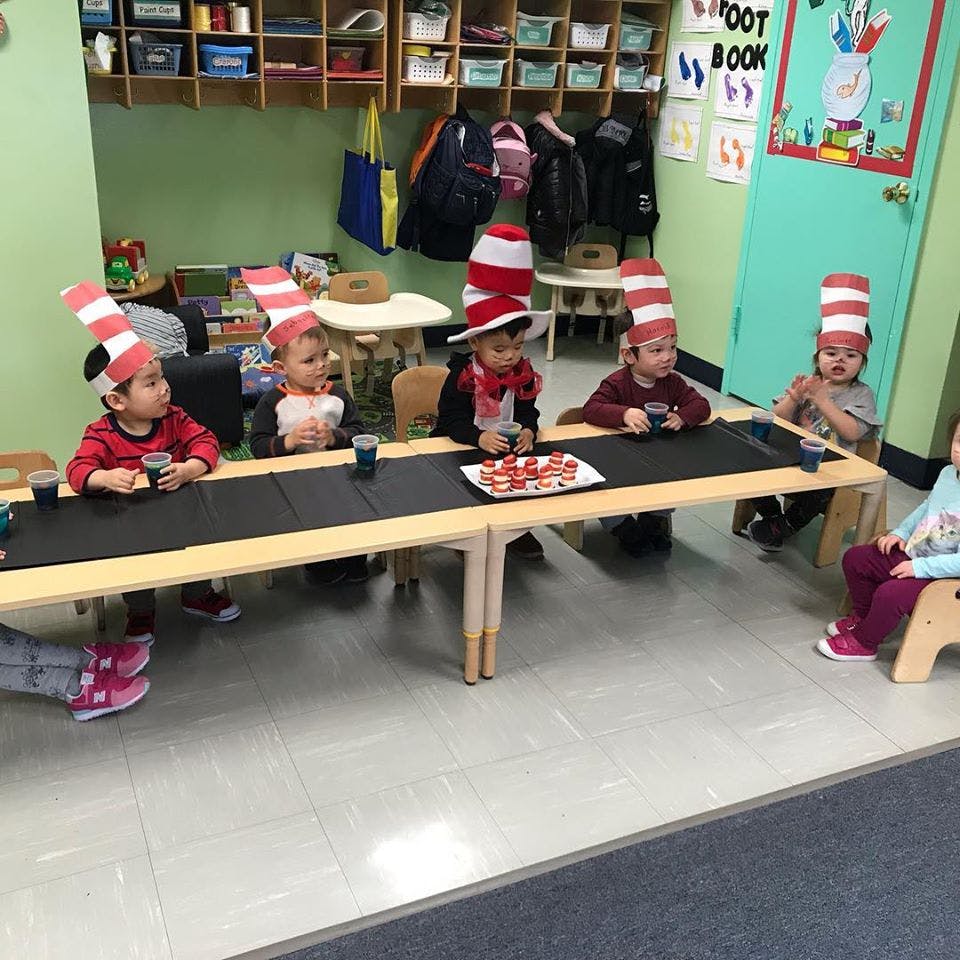 Children wearing striped hats sitting at a table in a classroom