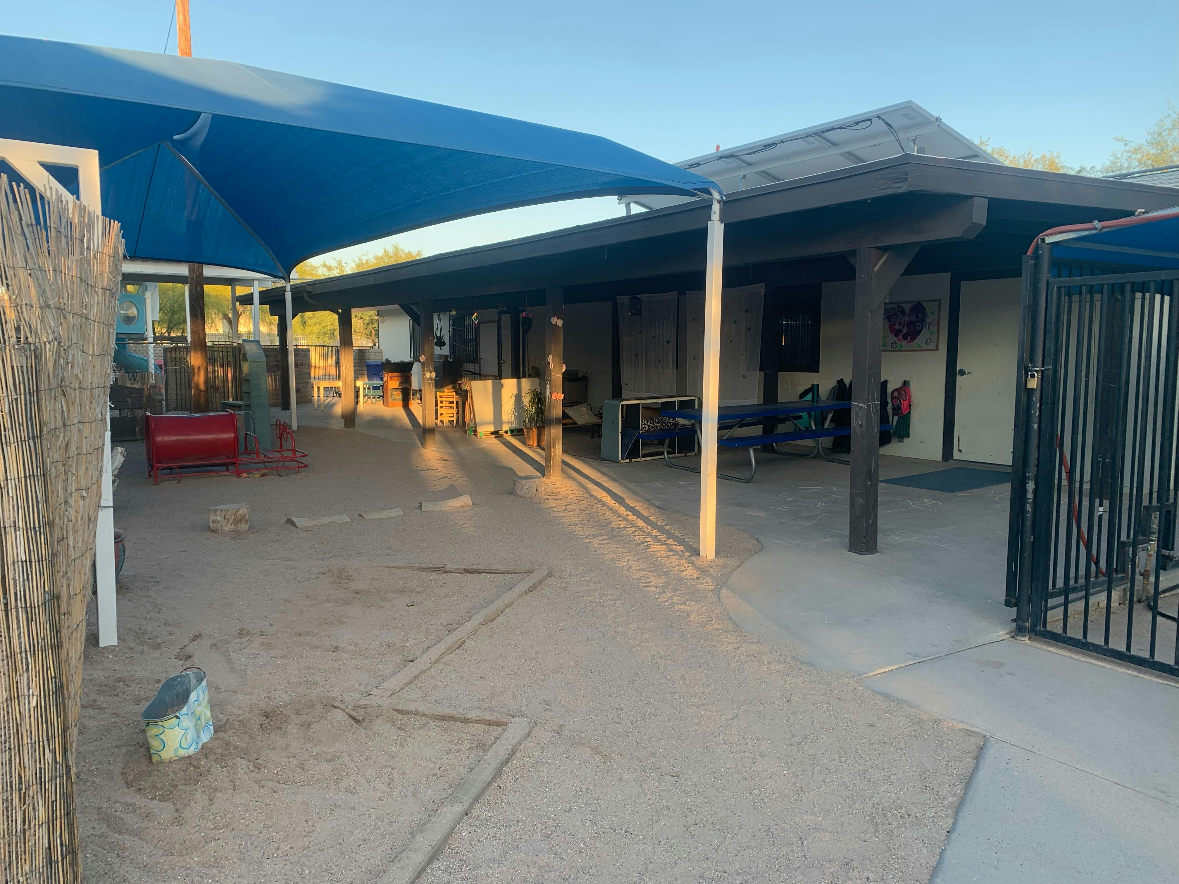 Outdoor play area with sand, shade structures, and building