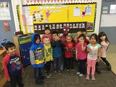 Children and a person in a Spiderman costume in a classroom