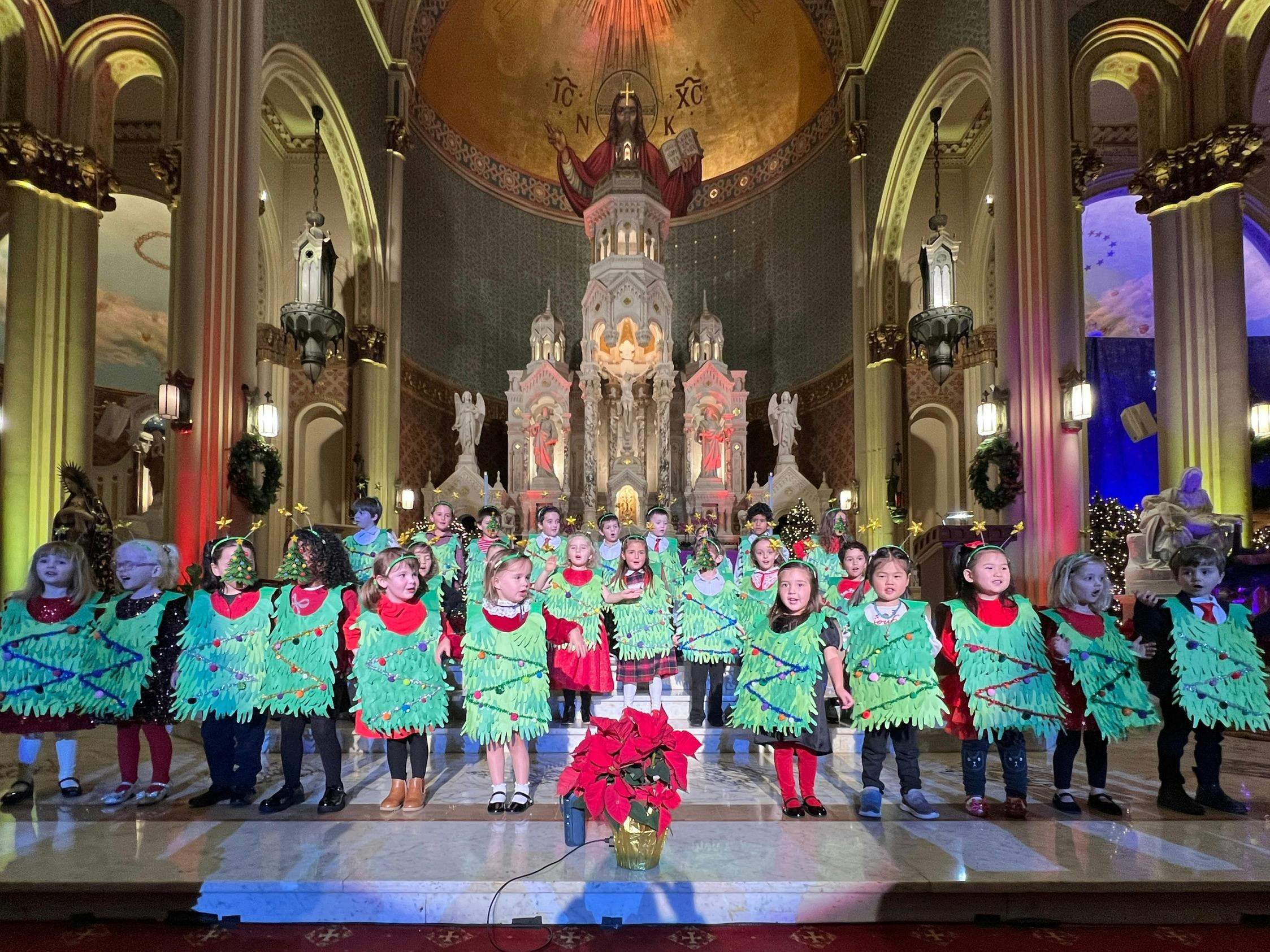 Children in green costumes on a stage in a large hall