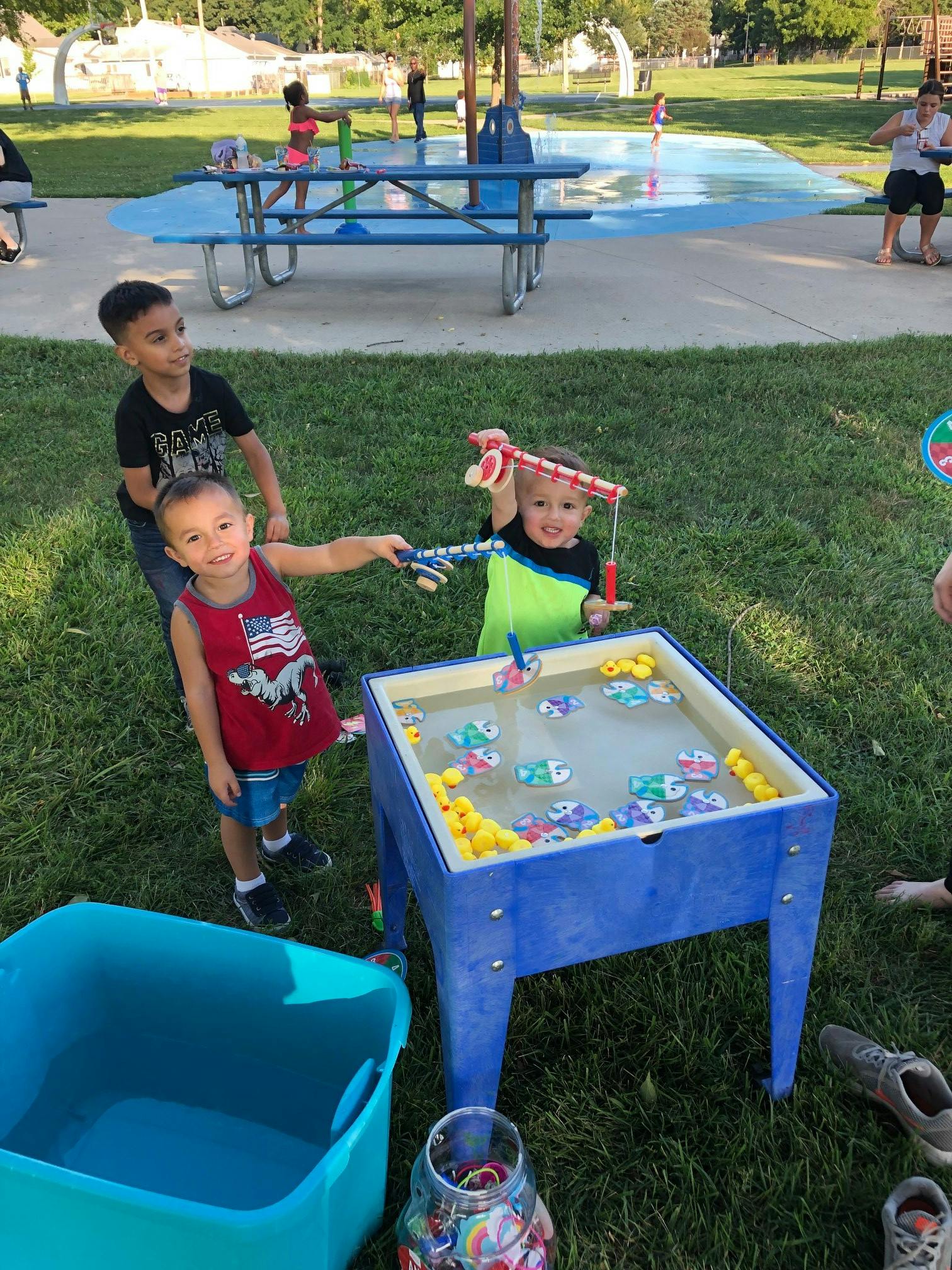 Three children playing with a water table and toy fishing poles